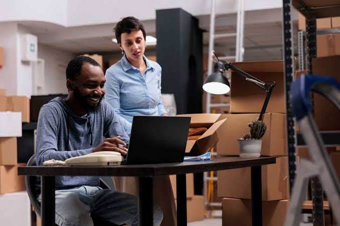 Two colleagues at a laptop in a small business storeroom